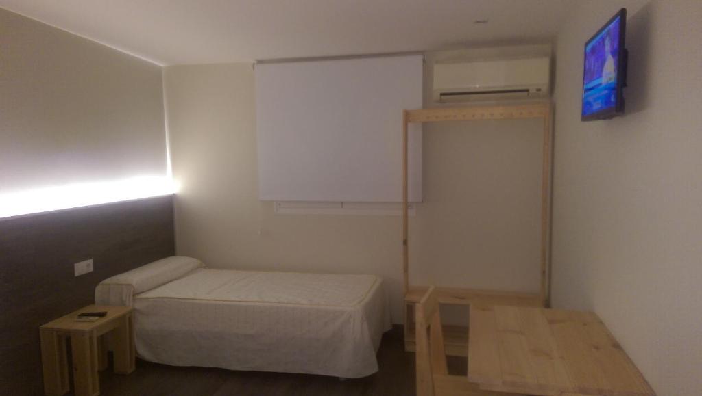 um pequeno quarto com uma cama e uma televisão em El Raco De Navarrete em Cabanes