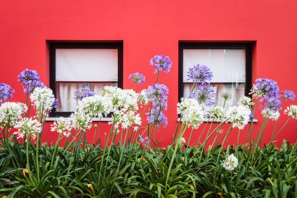 a red building with windows with flowers in front of it at Hotel Ibis Lisboa Sintra in Sintra