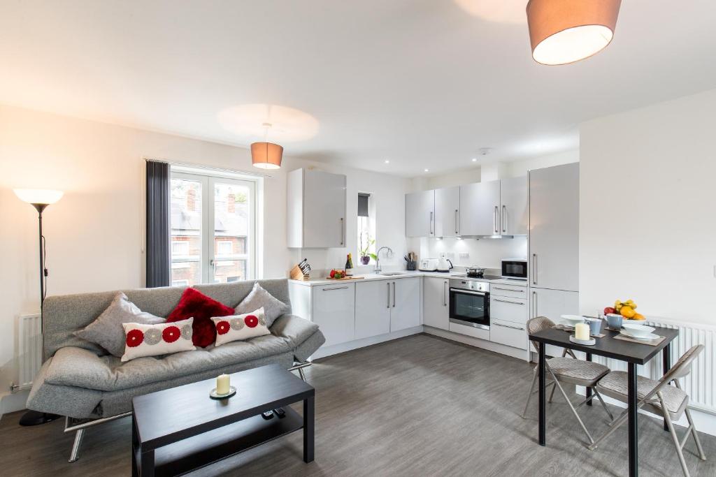 a living room with a couch and a kitchen at Abodebed Oval View Apartments in Hemel Hempstead