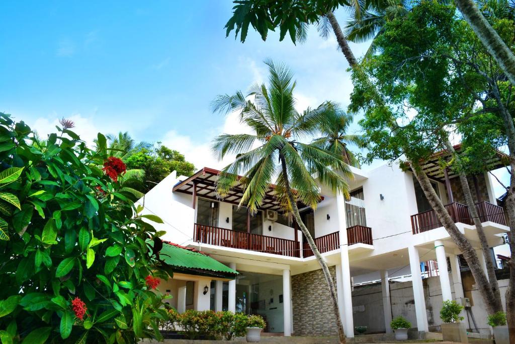 a building with palm trees in front of it at Sea View Tourist Inn in Tangalle