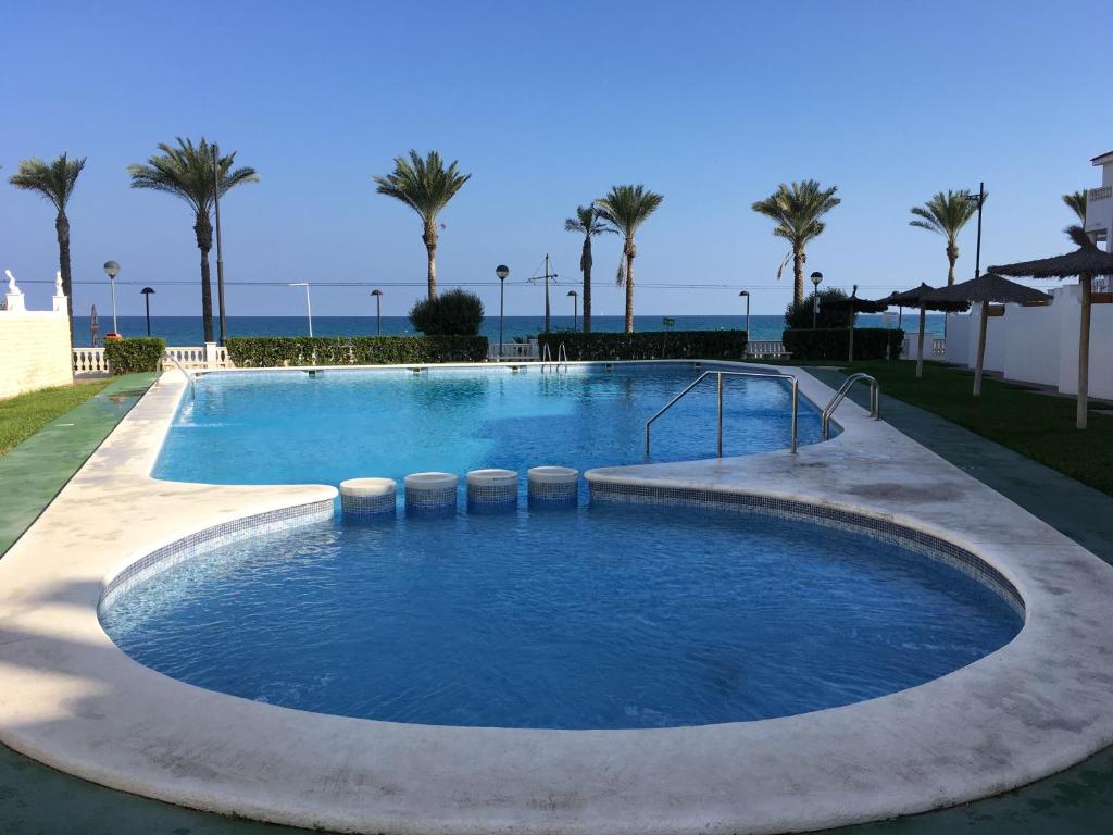 einen großen Pool mit Palmen und dem Meer in der Unterkunft Apartamento Roses in El Campello