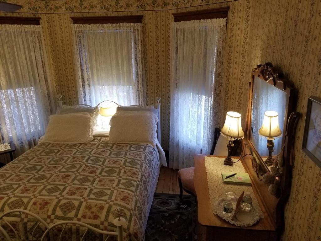 ein Schlafzimmer mit einem Bett und zwei Lampen auf einem Tisch in der Unterkunft Rose & Thistle Bed & Breakfast in Cooperstown