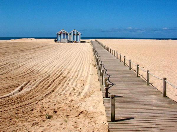 a wooden boardwalk on a beach with a building on it at NEW APT center 1 min walk beach/river/casino!!! in Figueira da Foz