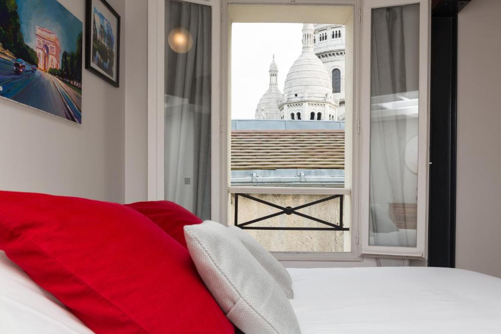 um quarto com uma almofada vermelha e vista para um edifício em Ateliers de Montmartre ADM em Paris