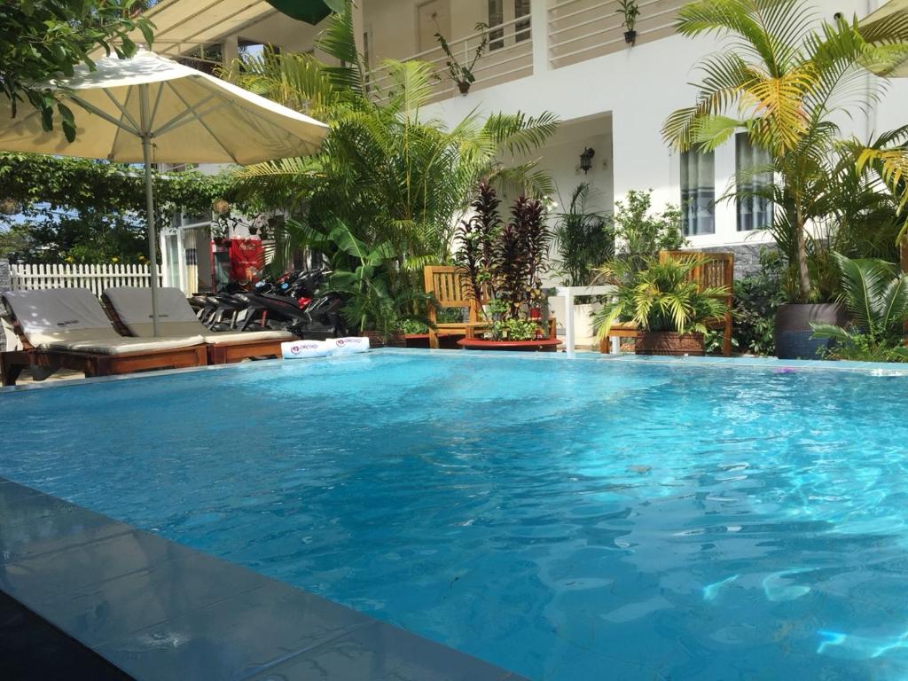 uma grande piscina com água azul em frente a um edifício em Orchid Guesthouse em Duong Dong