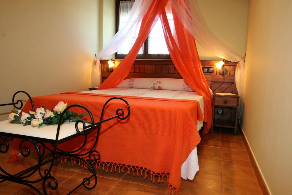 1 dormitorio con 1 cama con manta naranja y ventana en Apartamentos Toraya, en Hoz de Anero