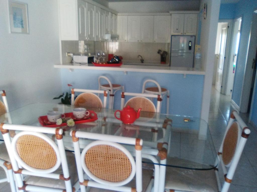プエルト・デ・ラ・クルスにあるapartamento en parque cardón Puerto cruzのガラステーブル、椅子、テーブル席付きのキッチンが備わります。