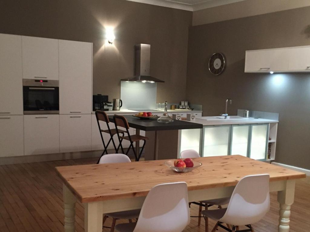 a kitchen with a wooden table and white cabinets at Boulevard Jules Ferry in Brive-la-Gaillarde