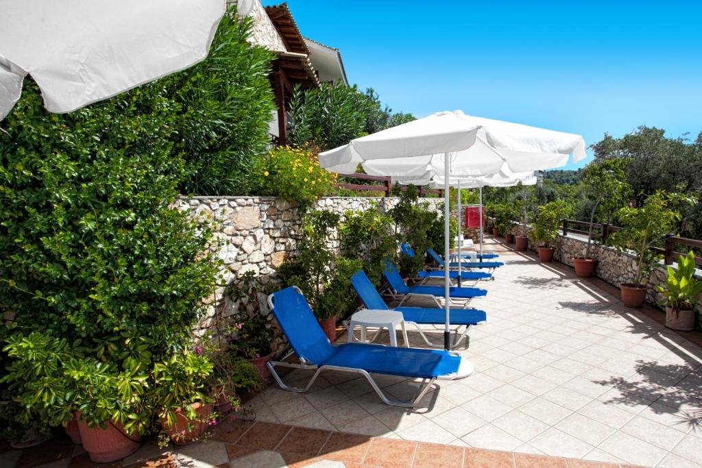 a row of blue chairs and umbrellas on a patio at Villa Maraki in Agia Paraskevi