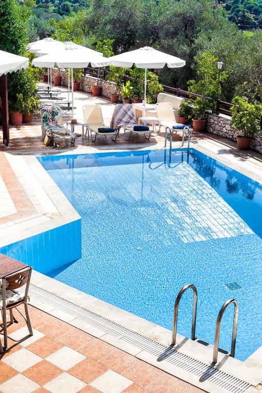 a large swimming pool with chairs and umbrellas at Villa Maraki in Agia Paraskevi
