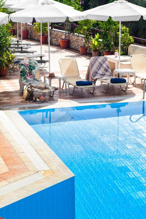 a swimming pool with lounge chairs and umbrellas next to a pool at Villa Maraki in Agia Paraskevi