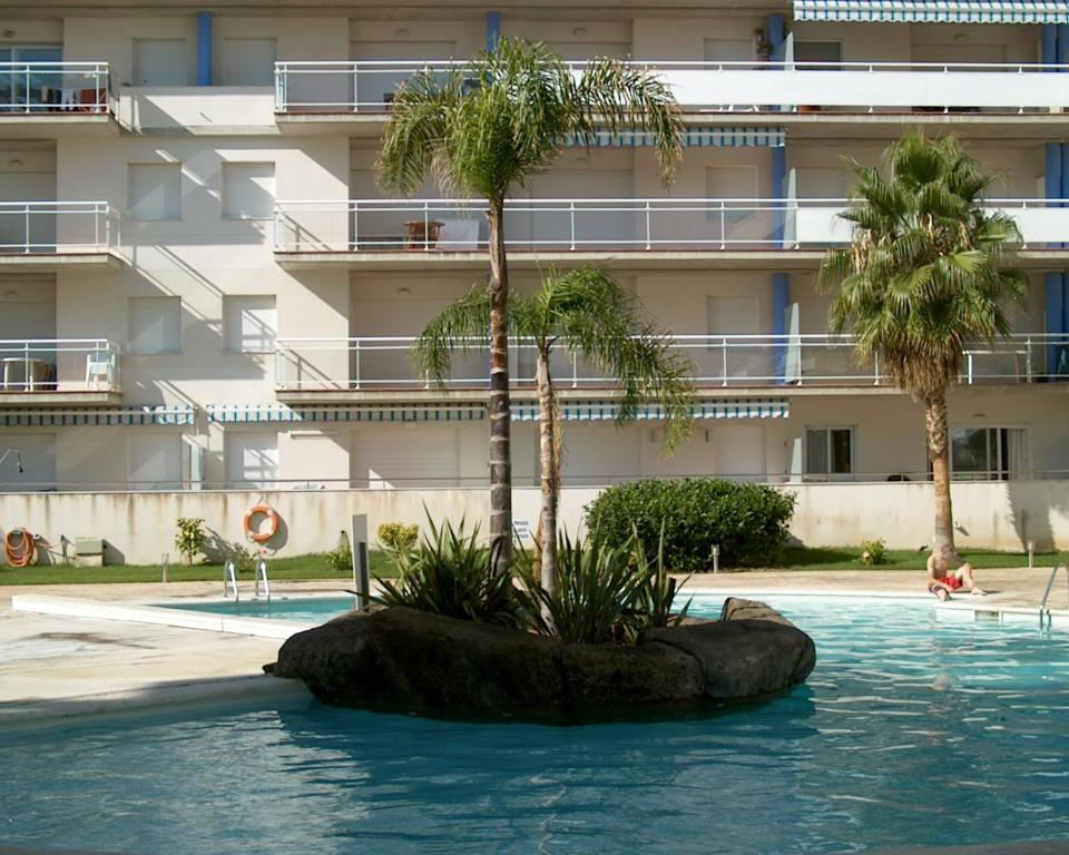 una piscina con dos palmeras y un edificio en APCOSTAS - Port Canigo, en Roses