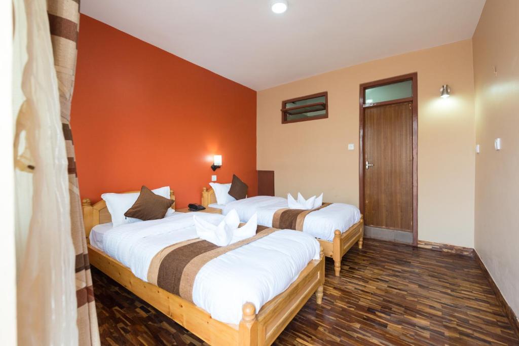2 Betten in einem Zimmer mit orangefarbenen Wänden in der Unterkunft Khangsar Home in Kathmandu