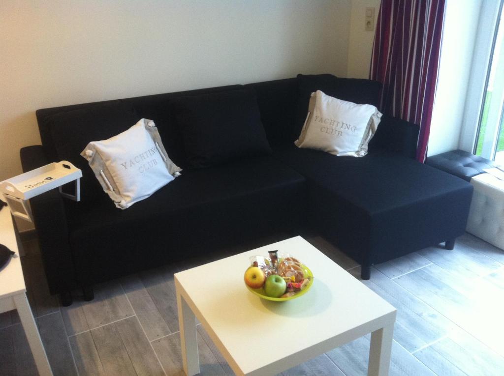 un sofá negro con un bol de fruta en una mesa en Vakantiestudio Melroce en Bredene