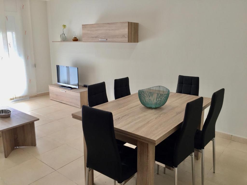 a dining room table with black chairs and a television at PISO CÉNTRICO DE 100 M2 in Girona