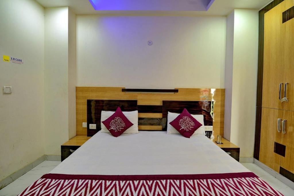 ein Schlafzimmer mit einem großen weißen Bett mit roten Kissen in der Unterkunft Goel Residency in Neu-Delhi