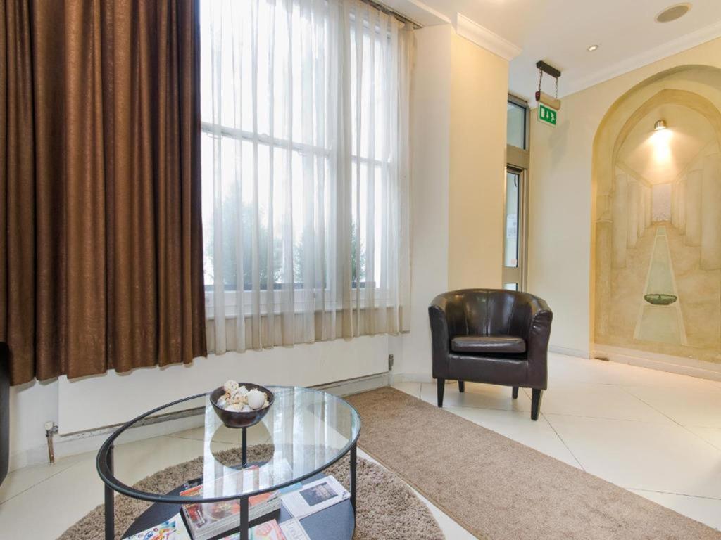 a living room with a glass table and a chair at The Royale Chulan Hyde Park Hotel in London