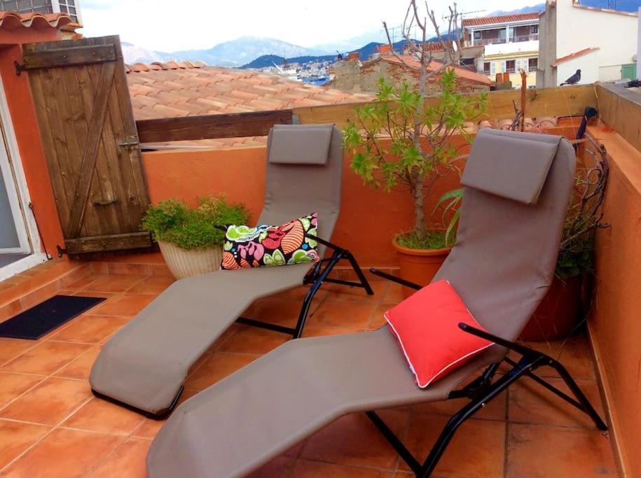 two chairs and a red book on a balcony at Studio loft avec terrasse centre historique in Ajaccio