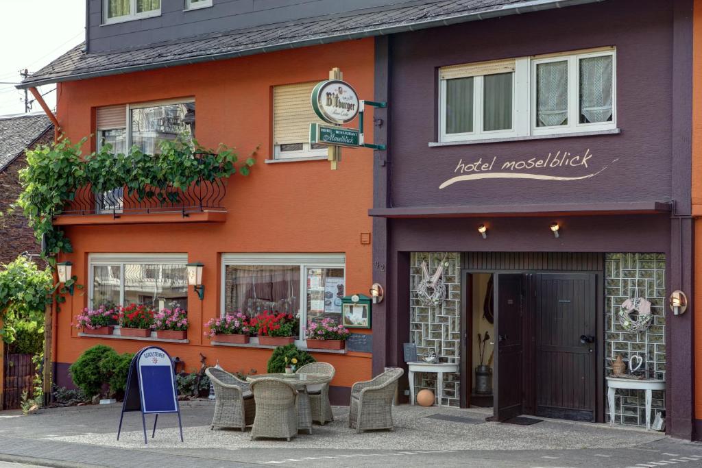 a building with a table and chairs in front of it at Hotel Restaurant Moselblick in Wintrich