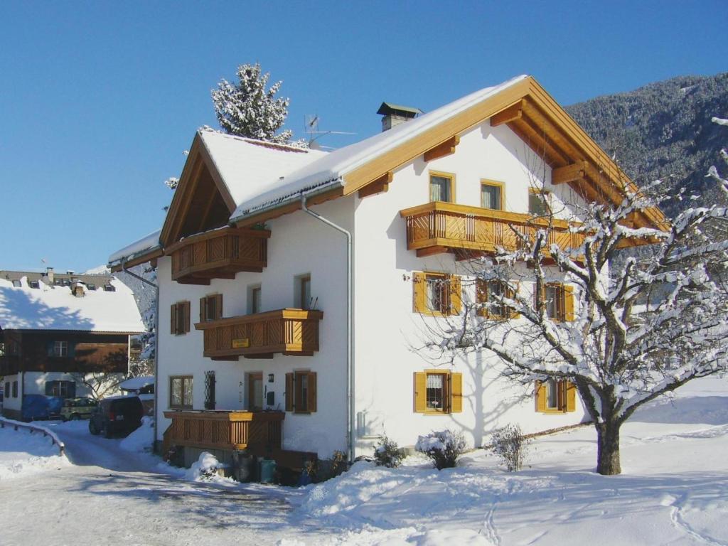 un edificio blanco con balcones de madera en la nieve en Appartements Wiesenheim, en Rasun di Sopra