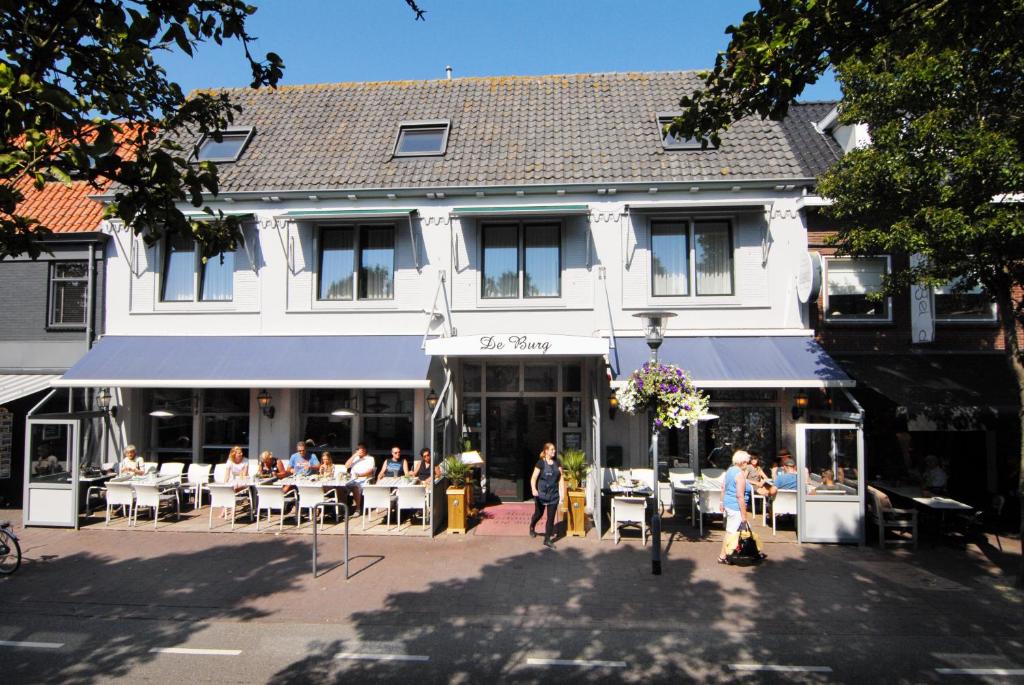 a group of people sitting at tables in front of a building at Hotel de Burg in Domburg