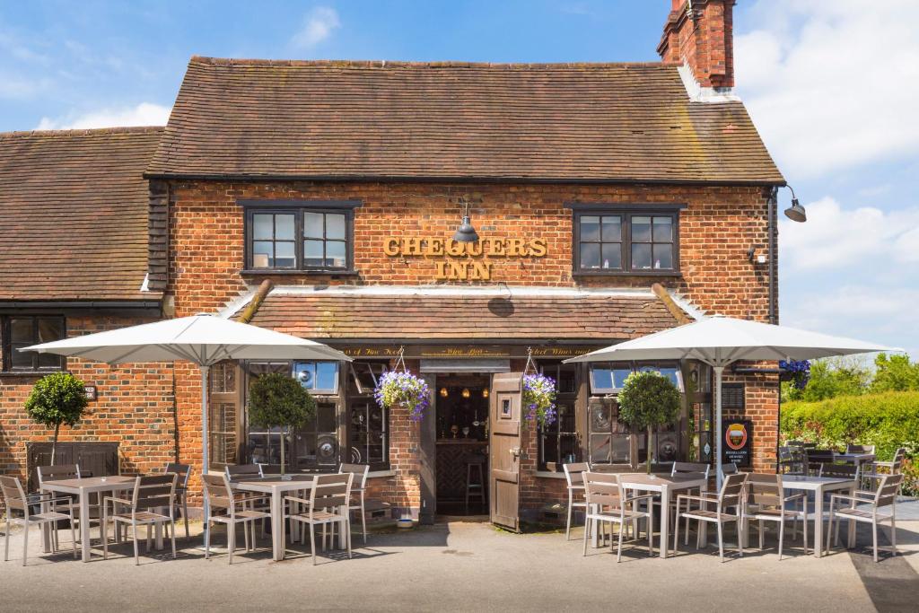 un restaurante con mesas y sombrillas frente a él en The Chequers Inn, en Beaconsfield