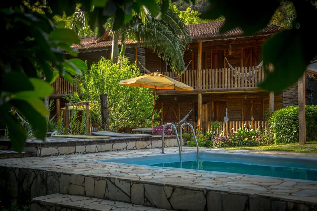 una piscina con sombrilla junto a una casa en Country Inn, Suites & Condo en São Pedro da Serra
