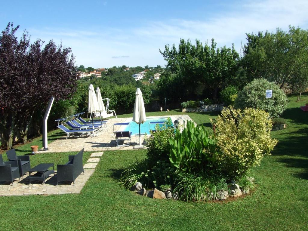 a pool with chairs and umbrellas in a yard at Villa Elda in Motovun