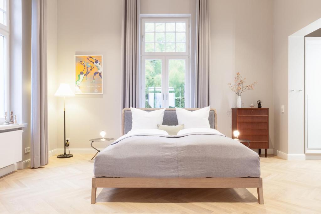 a white bedroom with a large bed and a window at OSTKÜSTE - Villa Staudt Design Apartments in Heringsdorf
