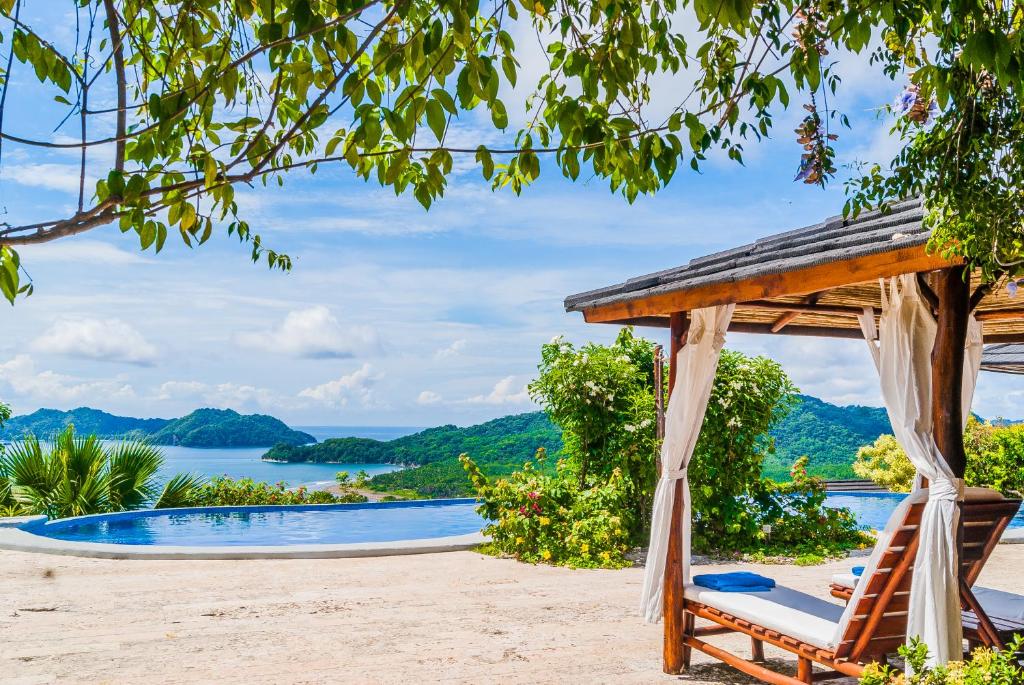 a hammock and a gazebo on a beach next to a pool at Eco Boutique Hotel Vista Las Islas Reserva Natural in Paquera