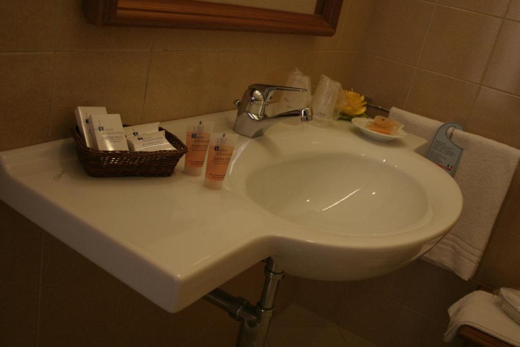 a bathroom sink with a basket of cosmetics on it at Hotel Centro di Spiritualità Padre Pio in San Giovanni Rotondo