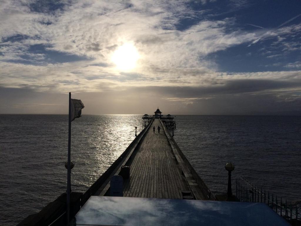 a pier in the ocean with the sun in the sky at The Nook @ Drop Anchor in Portishead