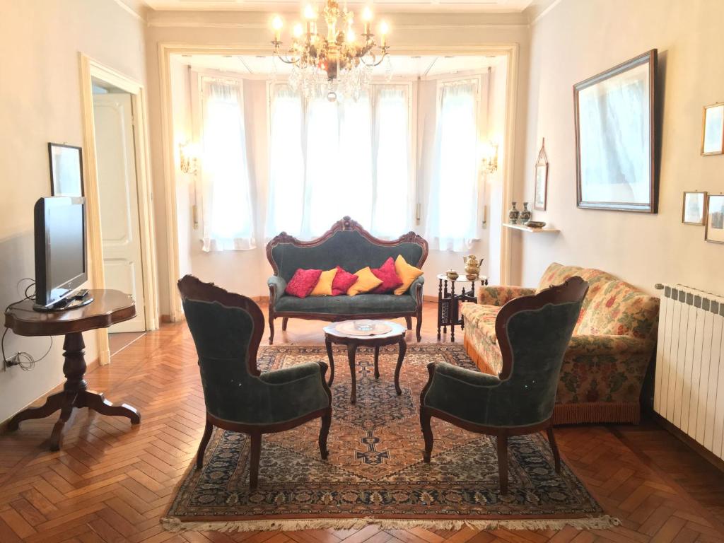 een woonkamer met een bank en stoelen en een tv bij La Casa di Sara in Genua