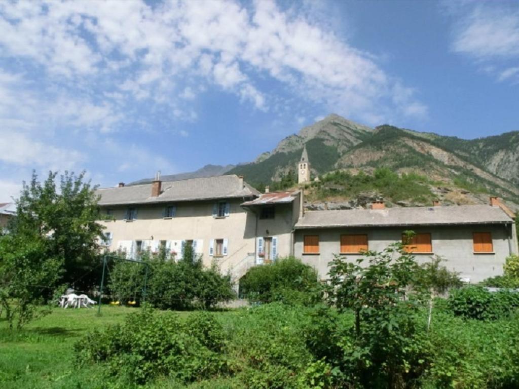 un gran edificio blanco con una montaña en el fondo en Lou Filadour 1ère Etage 5 personnes en Jausiers