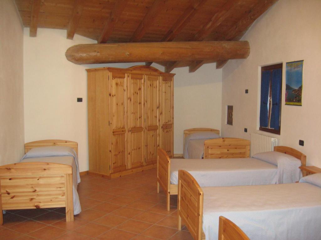 Habitación con 4 camas y muebles de madera. en Antica Osteria Pace en Moerna
