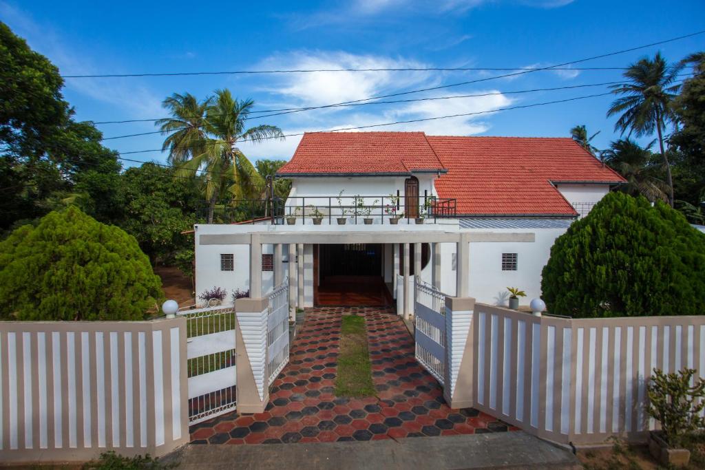 Casa blanca con techo rojo en Dayanithi Guest House, en Jaffna