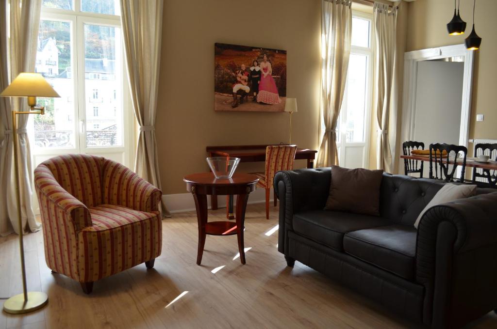 ein Wohnzimmer mit einem Sofa, Stühlen und einem Tisch in der Unterkunft L'Empereur, sa Femme et le petit Prince in Plombières-les-Bains