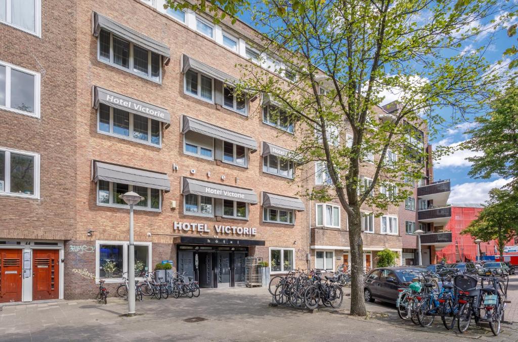 een bakstenen gebouw met buiten geparkeerde fietsen bij Hotel Victorie in Amsterdam