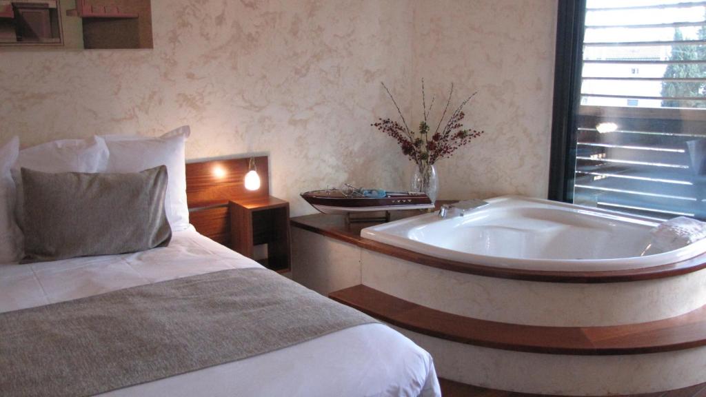 Ile du Gua Suites في ناربون: غرفة نوم مع سرير وحوض استحمام