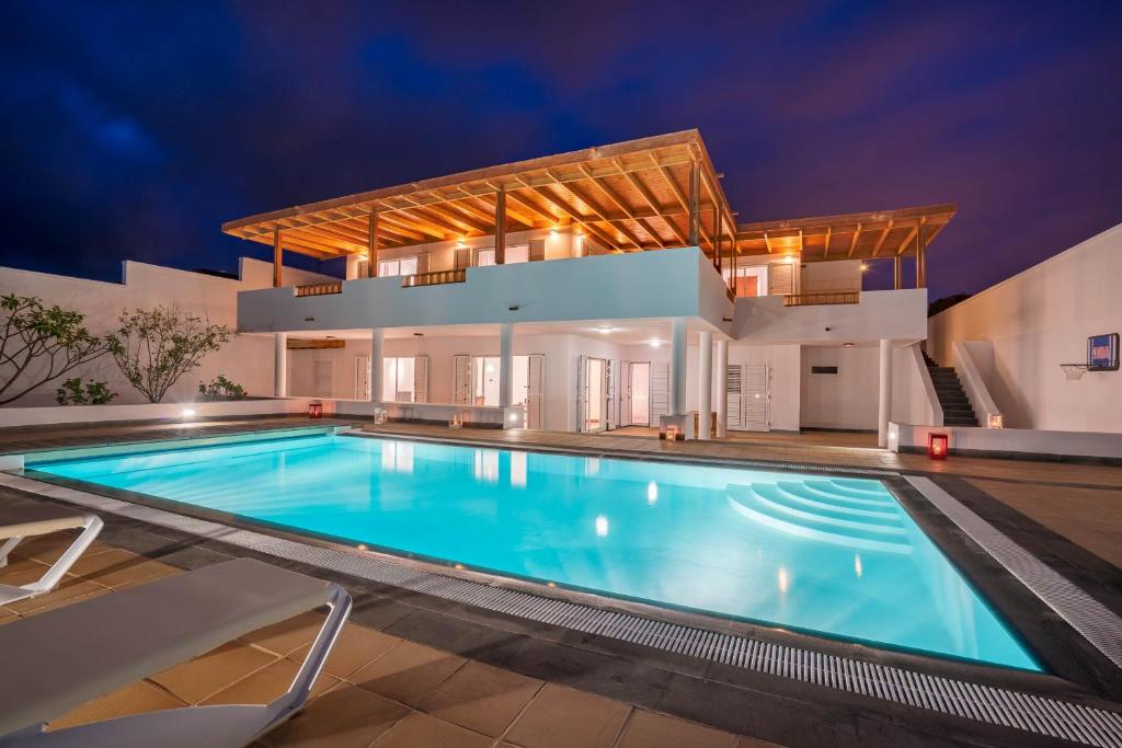 a swimming pool in front of a house at Villa Dedalos - A luxury large villa with a heated pool in Puerto Calero in Puerto Calero