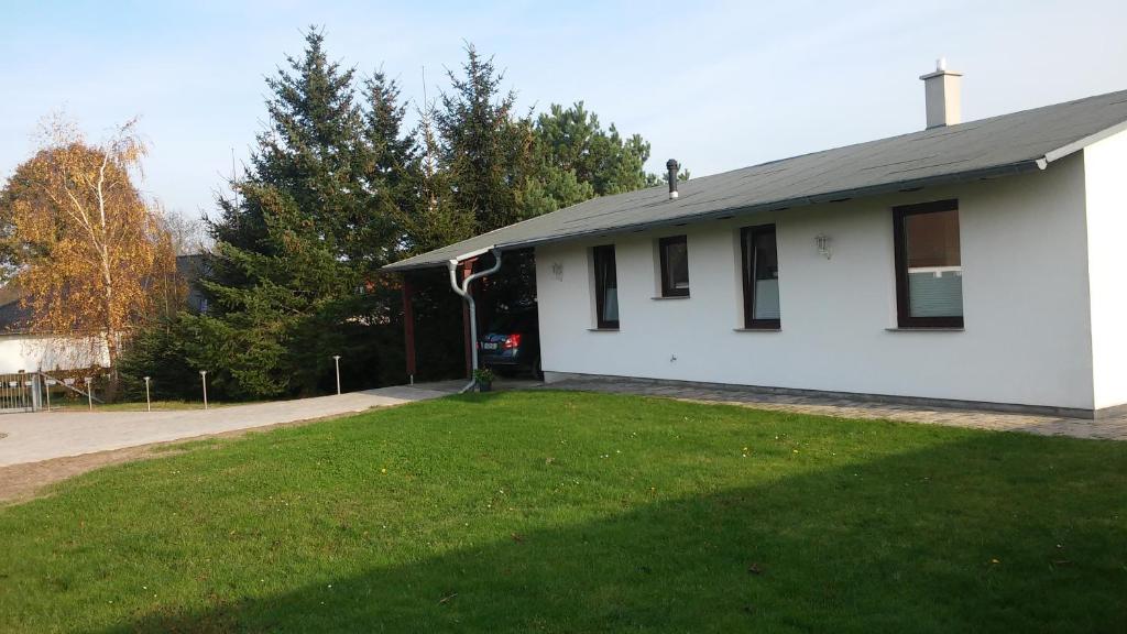 une maison blanche avec une pelouse verte devant elle dans l'établissement Ferienhaus Edeltraud, à Dargen