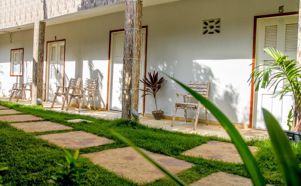 a patio of a house with chairs and grass at Pousada Barros in Jericoacoara