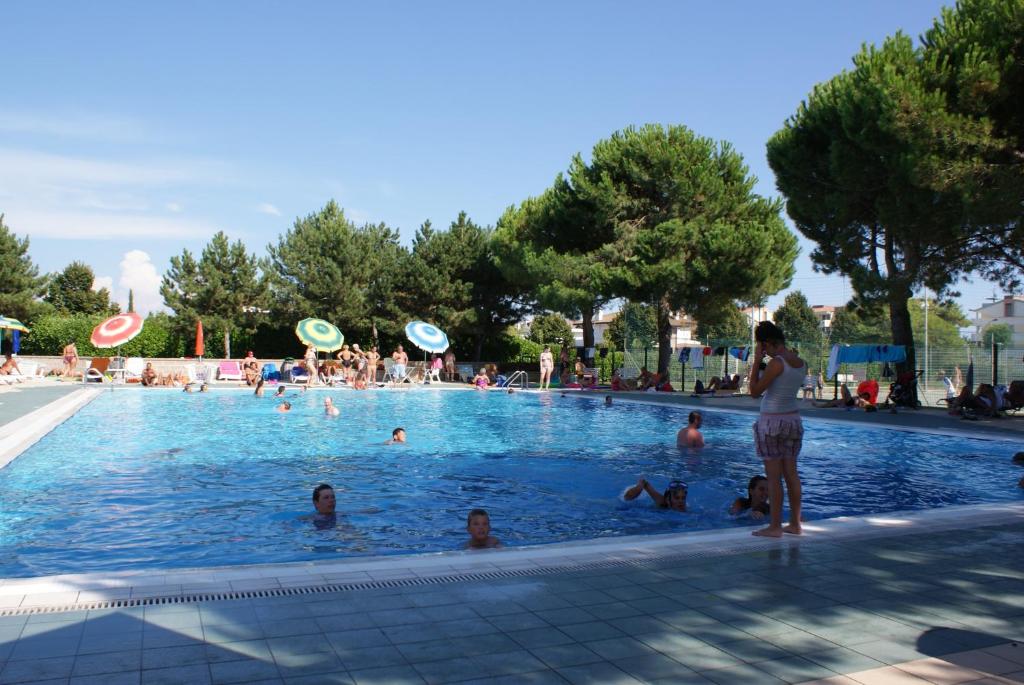 a woman standing in a swimming pool with people in it at Appartamenti Valbella in Bibione