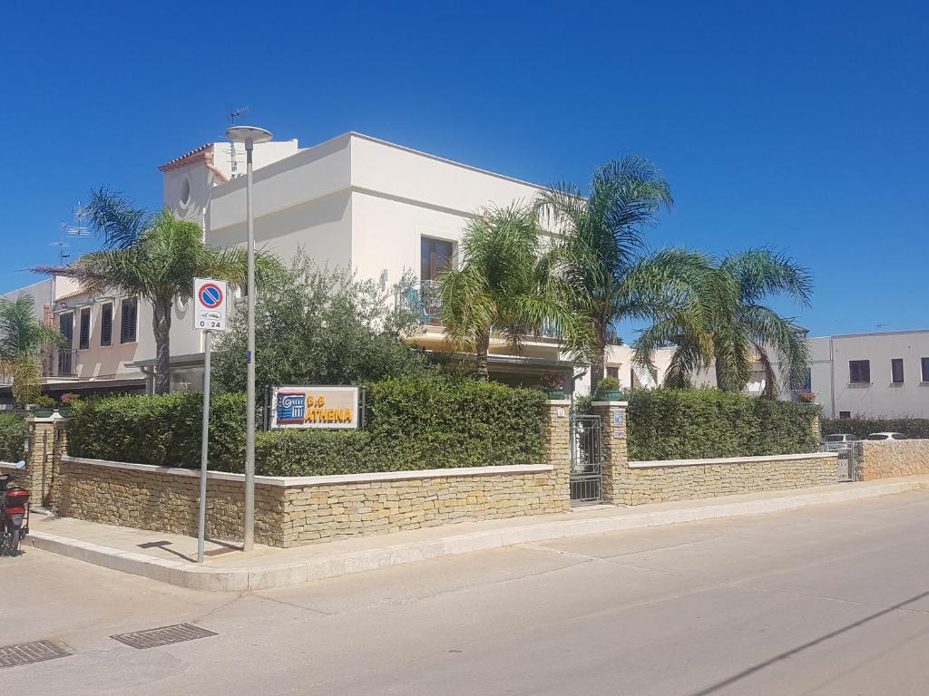 a building with palm trees on the side of a street at Athena Bed & Breakfast in San Vito lo Capo