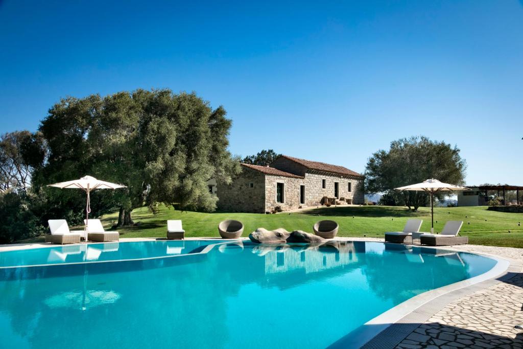 ein Pool mit Stühlen und Sonnenschirmen vor einem Haus in der Unterkunft Stazzo Lu Ciaccaru in Arzachena