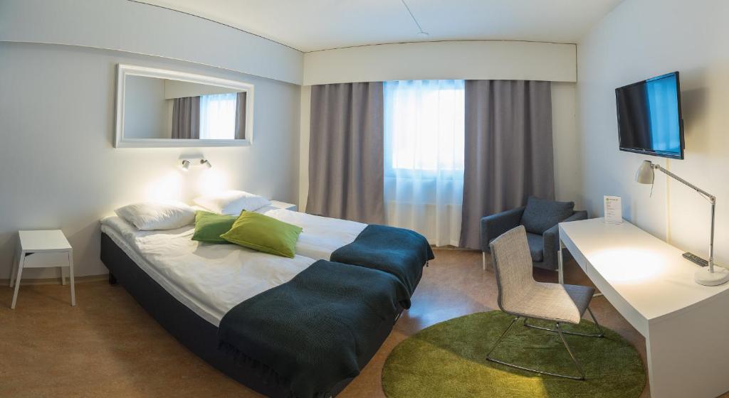 Hotel Kittilä في كيتيلا: غرفة الفندق بسرير كبير ومكتب