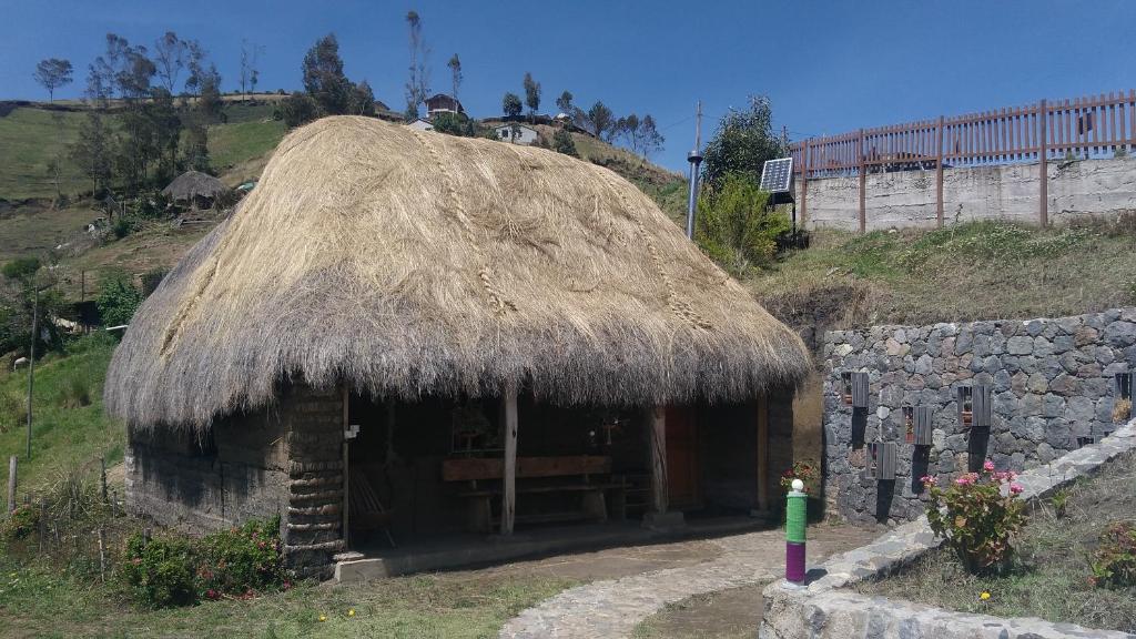 Hacienda Colta的住宿－Turismo Comunitario La Esperanza，山坡上带草屋顶的小小屋