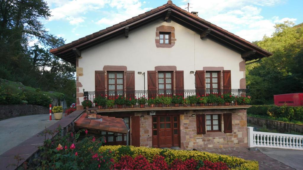 una casa con un balcón con flores. en Bizentenea, en Zugarramurdi