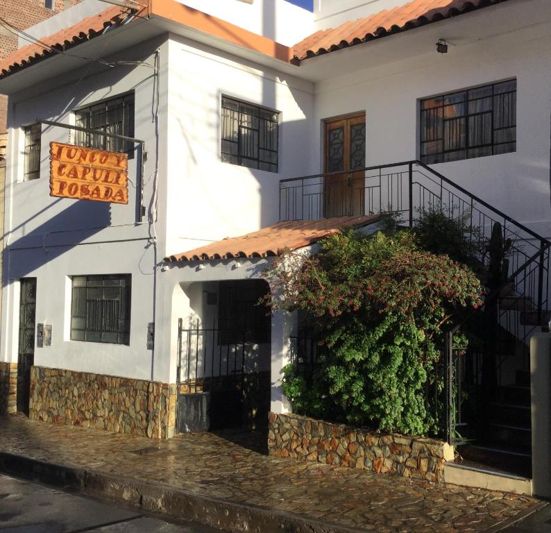 a white building with a sign on the side of it at Posada Junco y Capuli in Huancayo