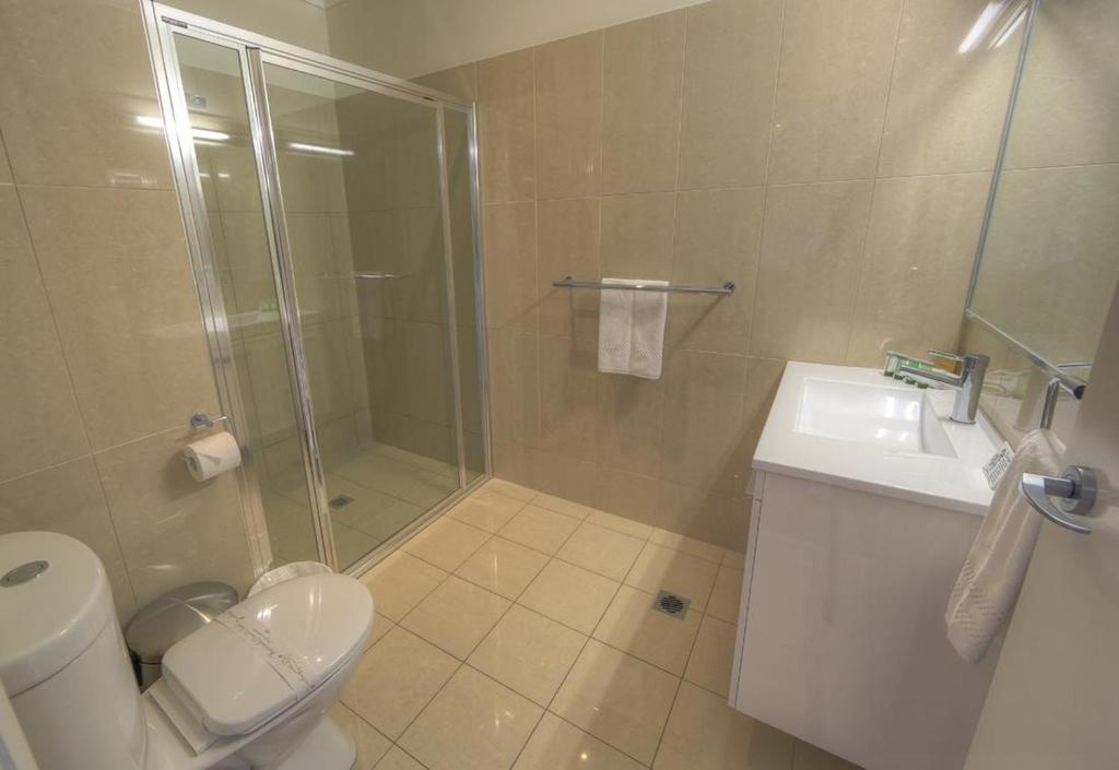 a bathroom with a shower and a toilet and a sink at Red Earth Motel in Broken Hill